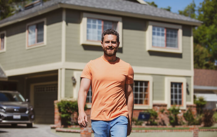 Smiling man in front of a house, representing homeowner first home tips.