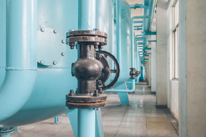 Blue industrial pipes indoors, focusing on a central black valve, relevant for homeowner-first-home-tips.