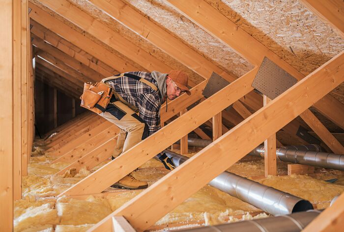 Person inspecting attic insulation, demonstrating first home tips for new homeowners.