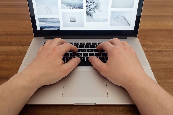 Hands typing on a laptop with home images on the screen, providing tips for first-time homeowners.