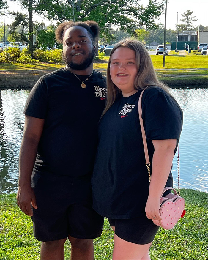 Two people smiling by a lake, both wearing black "Have a Nice Day" t-shirts, illustrating Honey Boo Boo's life changes.