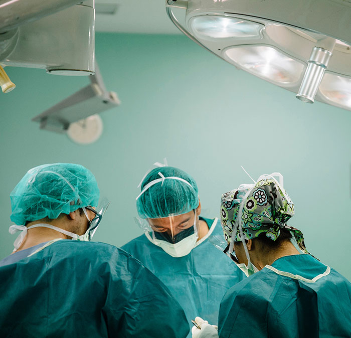 Medical students in a surgical setting, wearing scrubs and masks, under operating room lights. Medical students in a surgical setting, wearing scrubs and masks, under operating room lights.