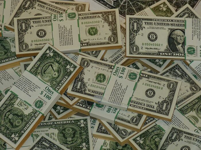 Stacks of one-dollar bills scattered, highlighting an unpopular opinion on financial priorities.
