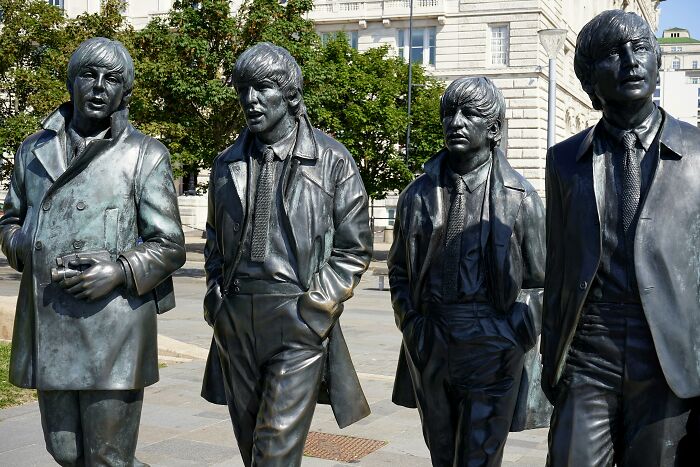 Statues of four musicians in coats, standing in an outdoor urban setting, representing an unpopular opinion theme.