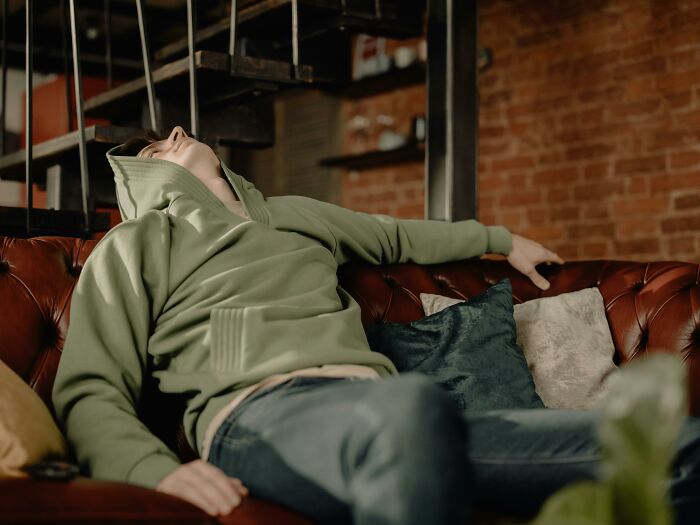 Person in a green hoodie taking a nap on a couch, illustrating the debate on the effectiveness of power naps.