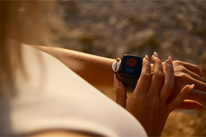 A person checks a smartwatch during sunset on the beach, symbolizing uncovering secrets and cheating partners.