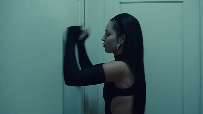 Person in a dark outfit knocks on a white door, expressing emotion related to exposing a cheating partner.