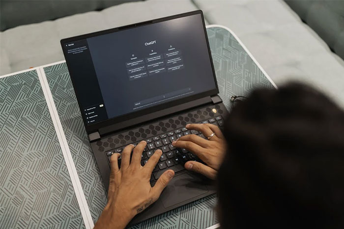 Person using laptop, likely exploring stories about exposing a cheating partner, on a patterned table surface.