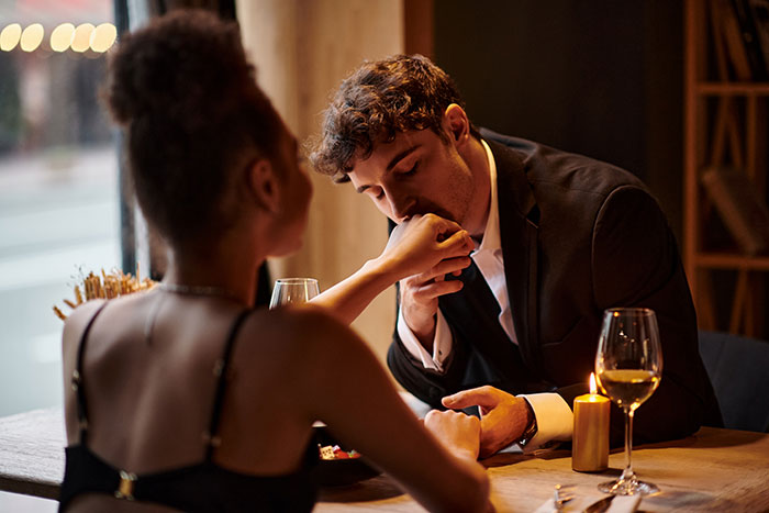 Couple sharing a romantic late-night drink as husband enjoys time with coworker in intimate restaurant setting.