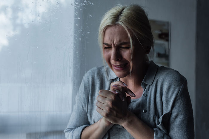 A woman in emotional distress stands near a rain-streaked window, highlighting miscarriage grief. A woman in emotional distress stands near a rain-streaked window, highlighting miscarriage grief.