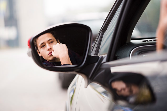 A person reflected in a car mirror, appearing deep in thought, symbolizing feeling smothered by frequent phone calls. A person reflected in a car mirror, appearing deep in thought, symbolizing feeling smothered by frequent phone calls.