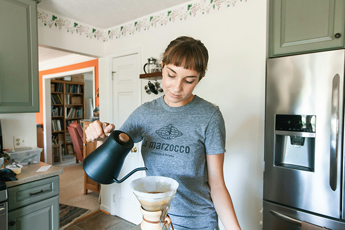 Woman in kitchen pouring water into coffee maker, illustrating husband therapist wife homework concept in a home setting. Woman in kitchen pouring water into coffee maker, illustrating husband therapist wife homework concept in a home setting.