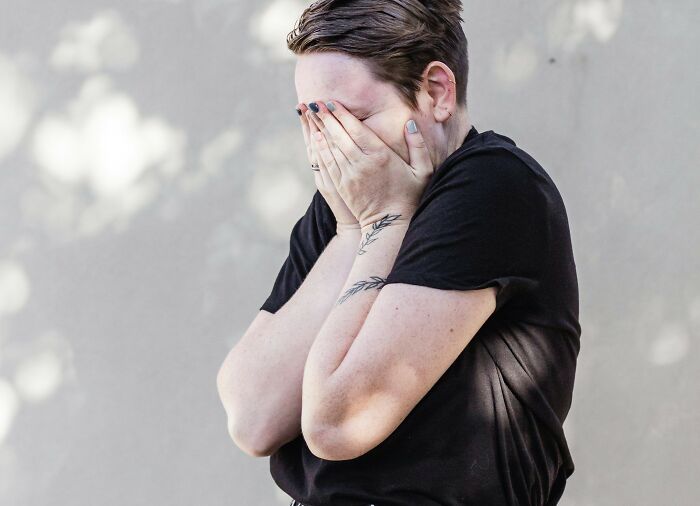 Woman in distress, covering face with hands, related to mortgage stress and expensive holiday dilemma.