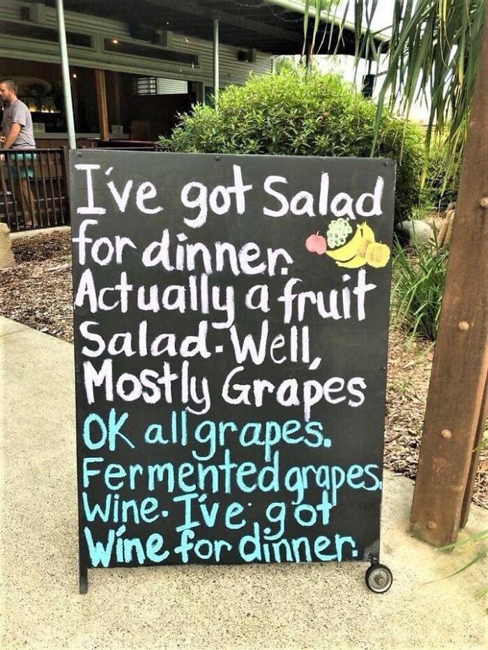 A humorous sign with sarcastic text about having wine for dinner instead of fruit salad.
