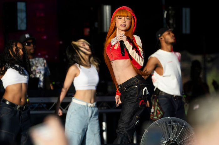 Ice Spice performing on stage in a red outfit with dancers, embodying Bronx rap energy.
