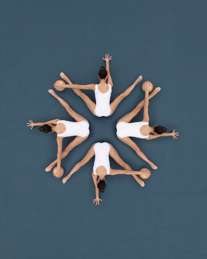 Aerial view of synchronized dancers in white leotards forming a star pattern on a blue background, showcasing conceptual photography.