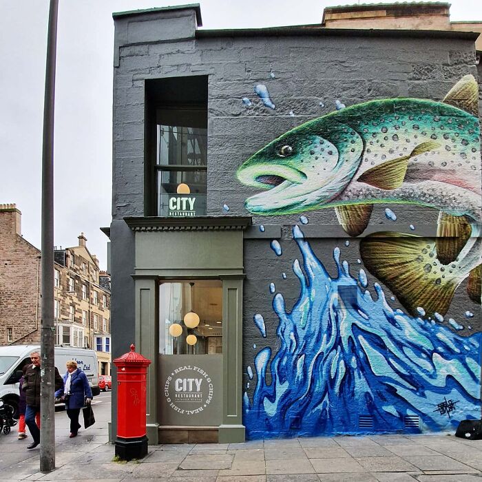 Colorful mural of a fish on a Glasgow wall, adding vibrancy to the urban scene near a red post box.
