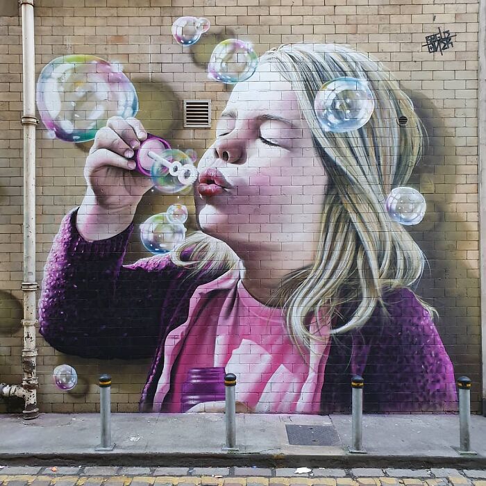 Girl blowing bubbles mural on a Glasgow wall, showcasing captivating street art.