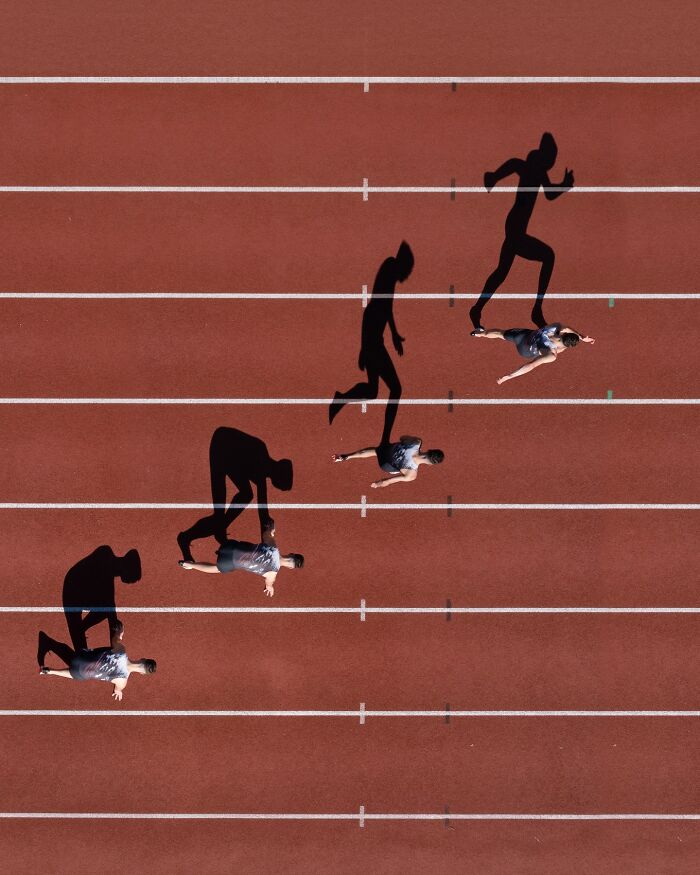 Aerial view of a runner on a track with dynamic shadows, showcasing conceptual photography by Brad Walls.