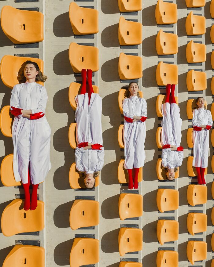 Aerial conceptual photography of people in white attire and red socks aligned on orange stadium seats by Brad Walls.
