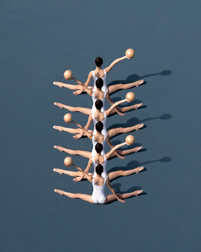 Aerial view of synchronized ballet dancers in white, holding balls, showcasing conceptual photography.