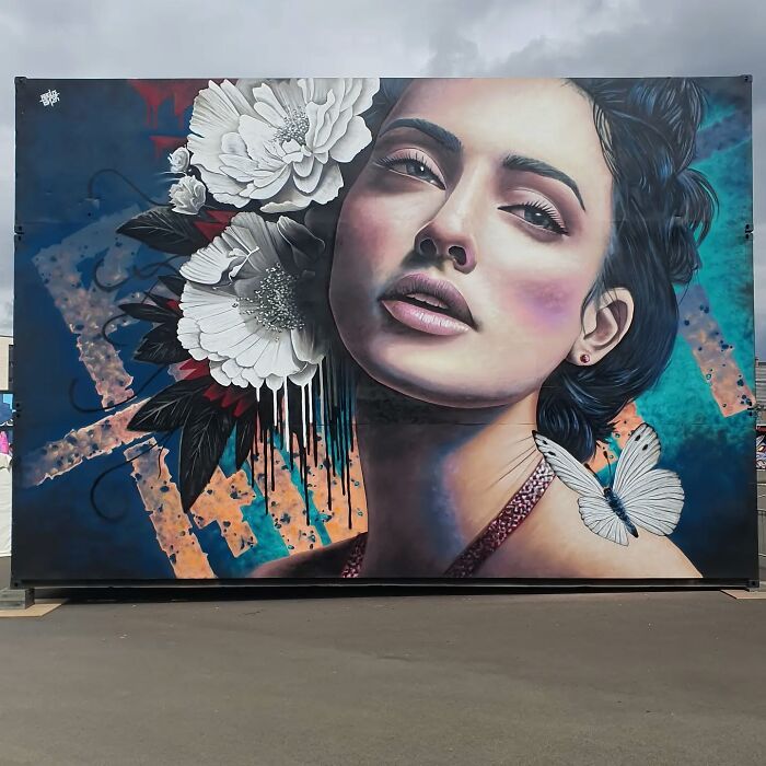 Mural of a woman's face with flowers and a butterfly on a wall in Glasgow.