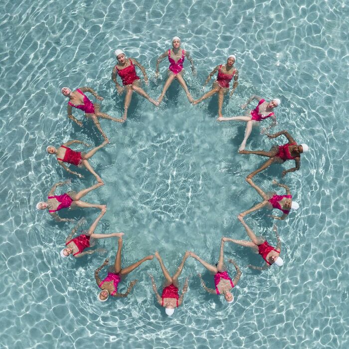 Aerial view of synchronized swimmers forming a star pattern in clear water, showcasing conceptual photography.