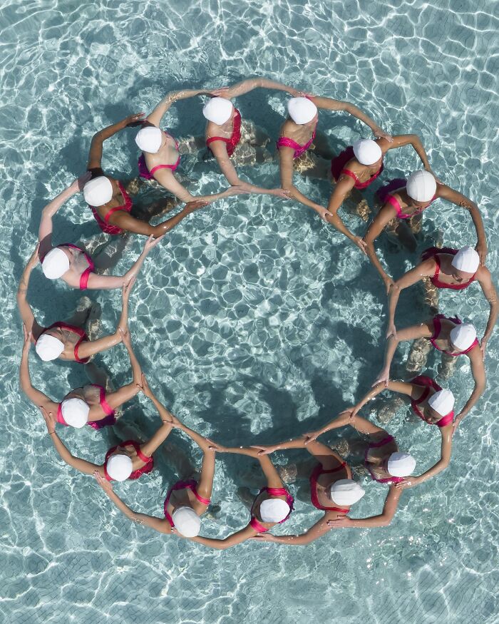Aerial shot of synchronized swimmers forming a circle in a pool, showcasing conceptual photography by Brad Walls.