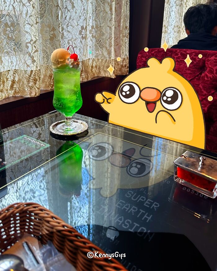 Cute cartoon bird beside a green soda with ice cream, sitting in a cozy cafe setting.