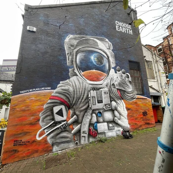 Astronaut mural on Glasgow wall, promoting environmental awareness with "Choose Earth" message.