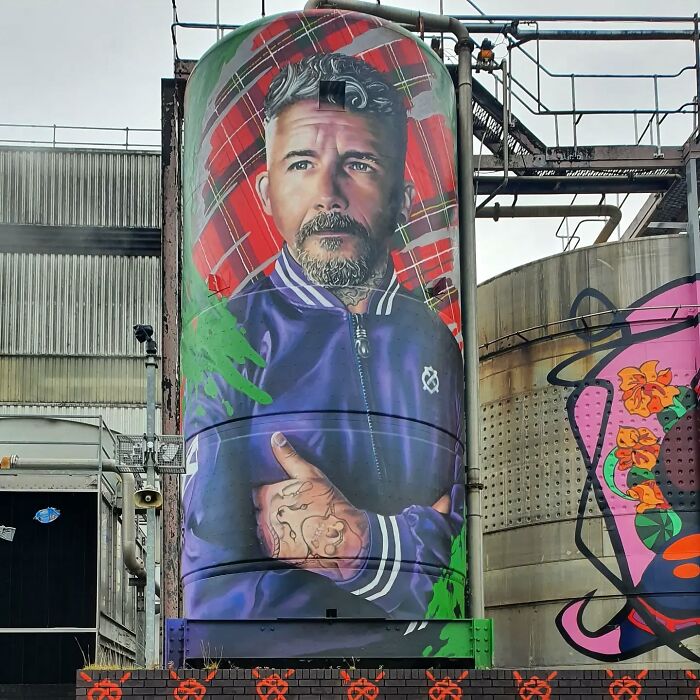 Captivating mural on a Glasgow building wall depicting a bearded man in a purple jacket.
