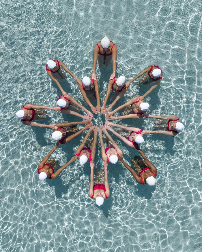 Aerial conceptual photography of swimmers in a star formation in a pool, showcasing creativity and symmetry.