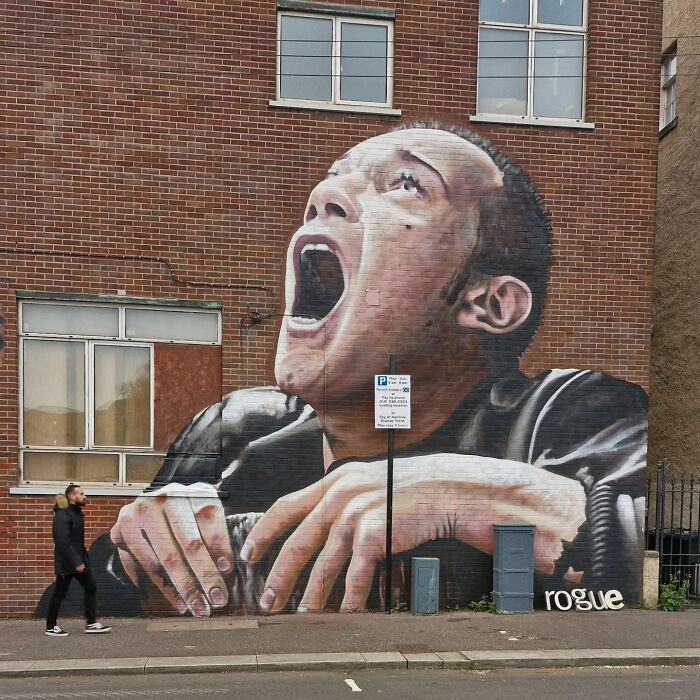 Giant mural on a Glasgow wall depicting a person shouting, showcasing urban street art.