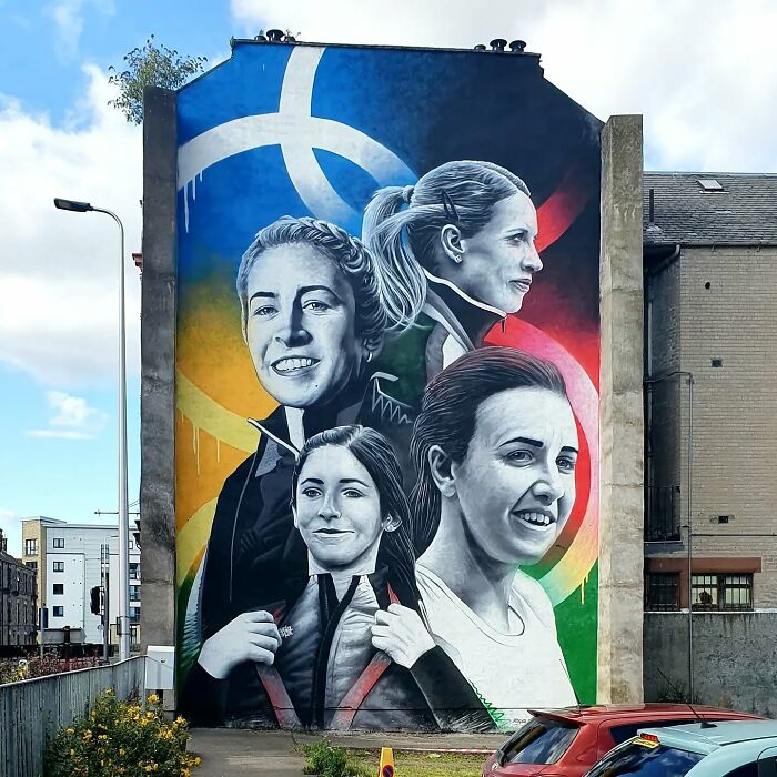 Colorful mural on Glasgow wall featuring portraits of four women, vibrant with abstract elements.