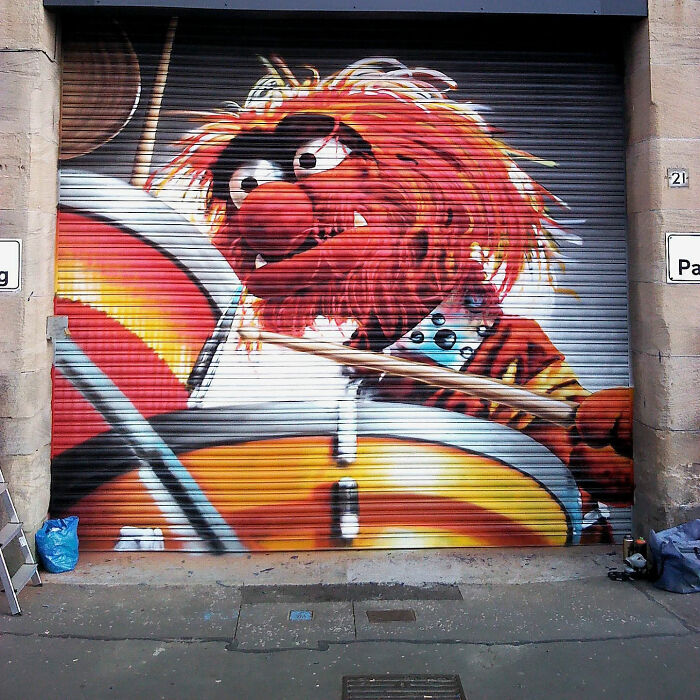 Colorful mural of a drummer character on a garage door in Glasgow.