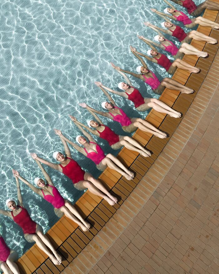 Aerial shot of synchronized swimmers in pink swimsuits by a pool, showcasing conceptual photography.