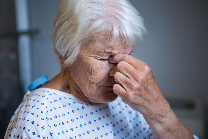 Elderly person in a hospital gown, appearing stressed, illustrating incorrect medical diagnosis.