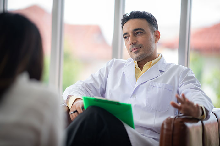 Doctor in white coat discussing medical diagnosis with a patient in an office setting.