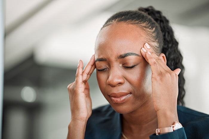 Person holding head in frustration, possibly due to an incorrect medical diagnosis, wearing a watch and blue clothing.