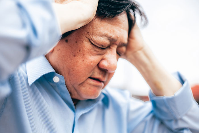Man in discomfort, holding his head, possibly reflecting on an incorrect medical diagnosis.