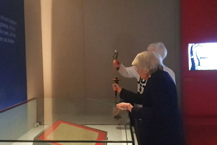 Two elderly tourists ignoring museum rules while touching exhibit, displaying entitled and rude behavior at the gallery.