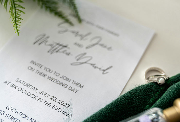 Wedding invitation with ring and greenery, evoking emotions of a bride whose future father-in-law invited unexpected guests.