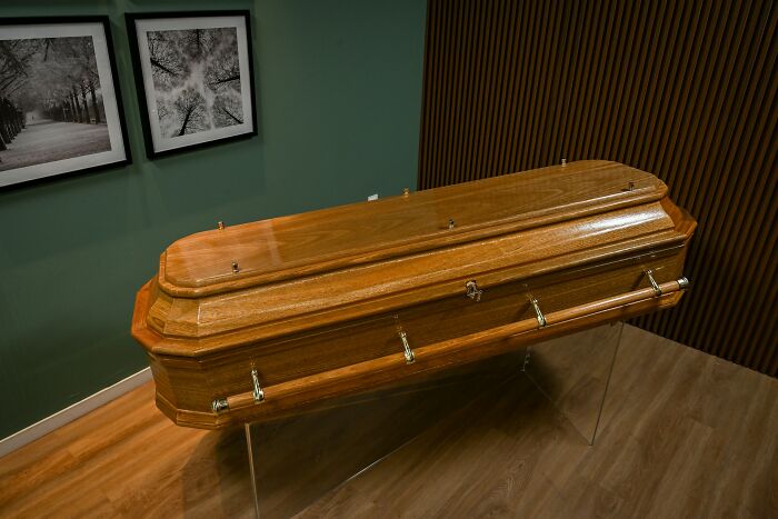 Wooden coffin in a room with framed pictures on the wall. Creepy discovery in someone's house.