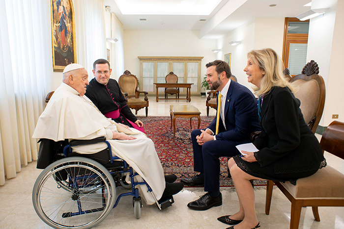 JD Vance meeting Pope Francis in a formal room, engaging in a seated conversation with others present.