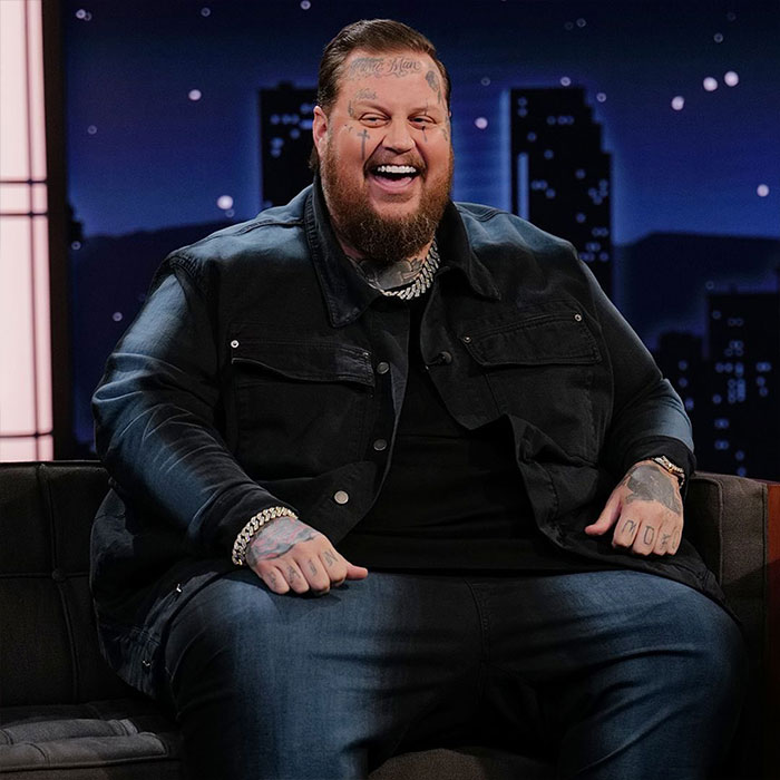 Jelly Roll smiling on a talk show, showcasing his transformation from rock bottom to rock star success.