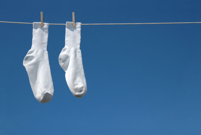 White socks on a clothesline against a clear blue sky, symbolizing a fresh start from rock bottom to rock star.