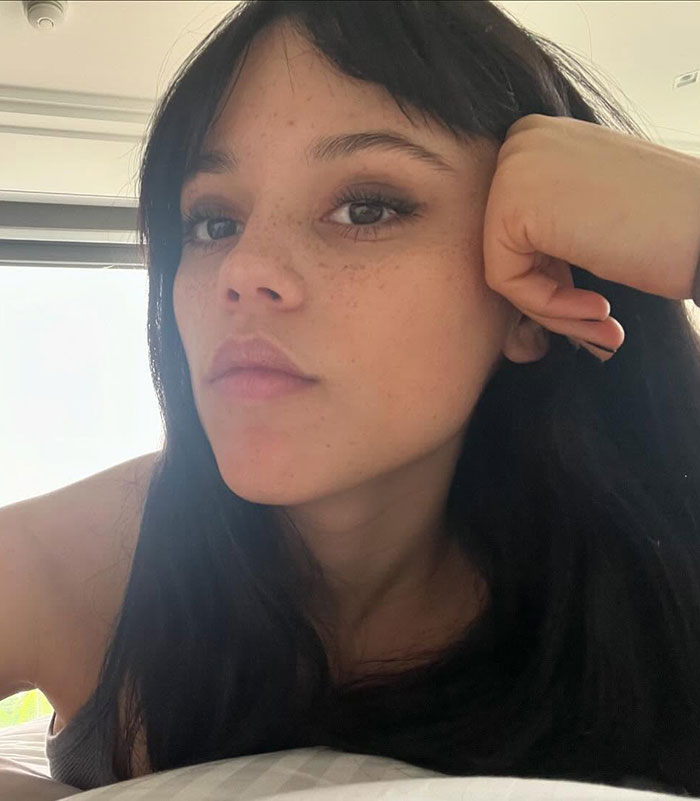 Young woman with long dark hair, lying down, looking thoughtful.