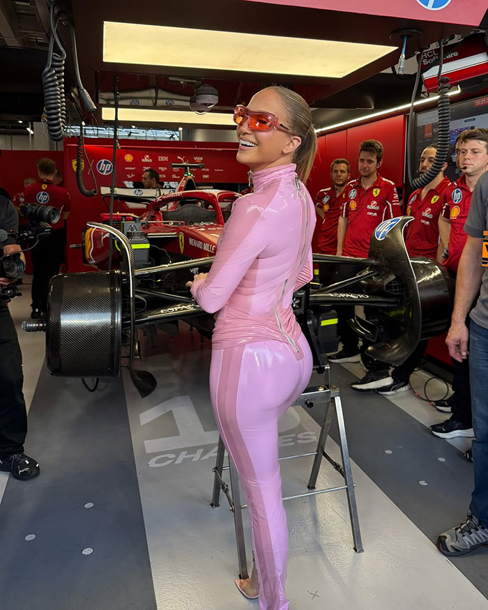 Person in pink catsuit at Saudi F1 race, standing by a car in the garage area, surrounded by team members.