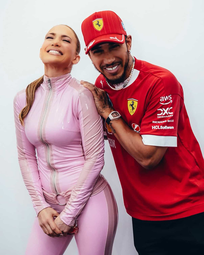 Woman in pink catsuit with athlete, both smiling at Saudi F1 race.