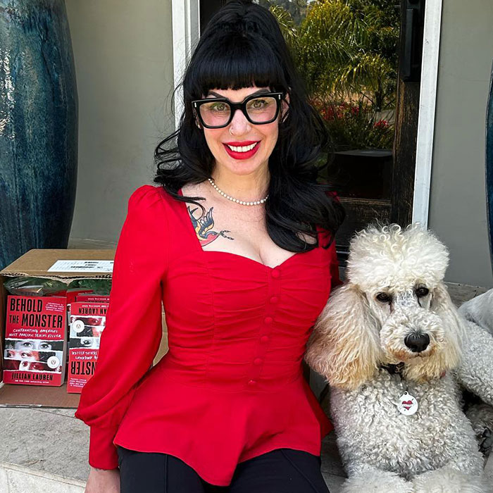 Woman in red dress with black glasses sitting next to a poodle, related to Weezer bassist's family incident in LA.
